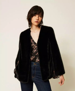 Model wearing the Twinset faux fur cape jacket featuring a plush texture, V-neckline, cape-style arm openings and straight silhouette.