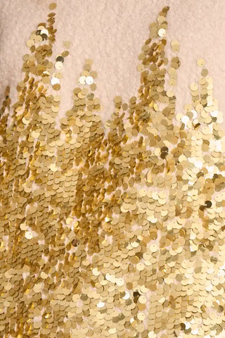 Close-up of gold sequins on a textured beige background