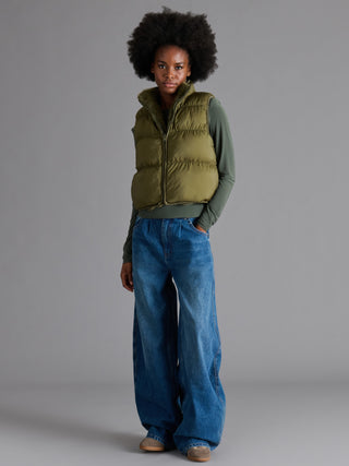 Woman wearing the Brady plush faux fur zip-front vest with a high collar, layered over a long sleeve top and wide-leg jeans