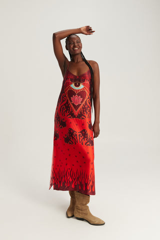 Woman wearing a red printed camisole maxi dress with adjustable straps, artistic print, and flowing silhouette.