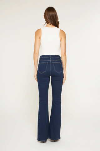 Person wearing blue flared jeans and a white top on a white background
