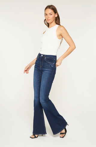 Woman wearing blue flared jeans and a white top on a white background