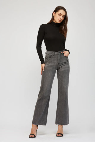 Woman wearing grey wash super high rise wide leg jeans with a cropped ankle-length silhouette and stretch denim fabric.