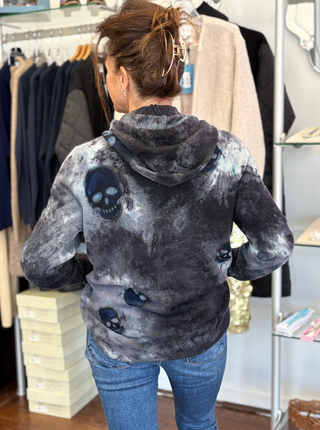 Person wearing a gray hoodie with skull designs in a clothing store.
