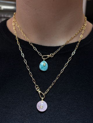 Layered gold chain necklaces featuring turquoise and pale pink quartz stone pendants with delicate crystal accents, styled over a black top.