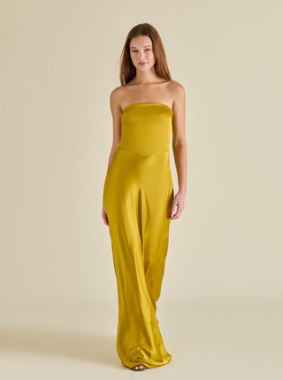 Woman wearing a strapless yellow stretch maxi dress with a fitted silhouette and floor-length hem.